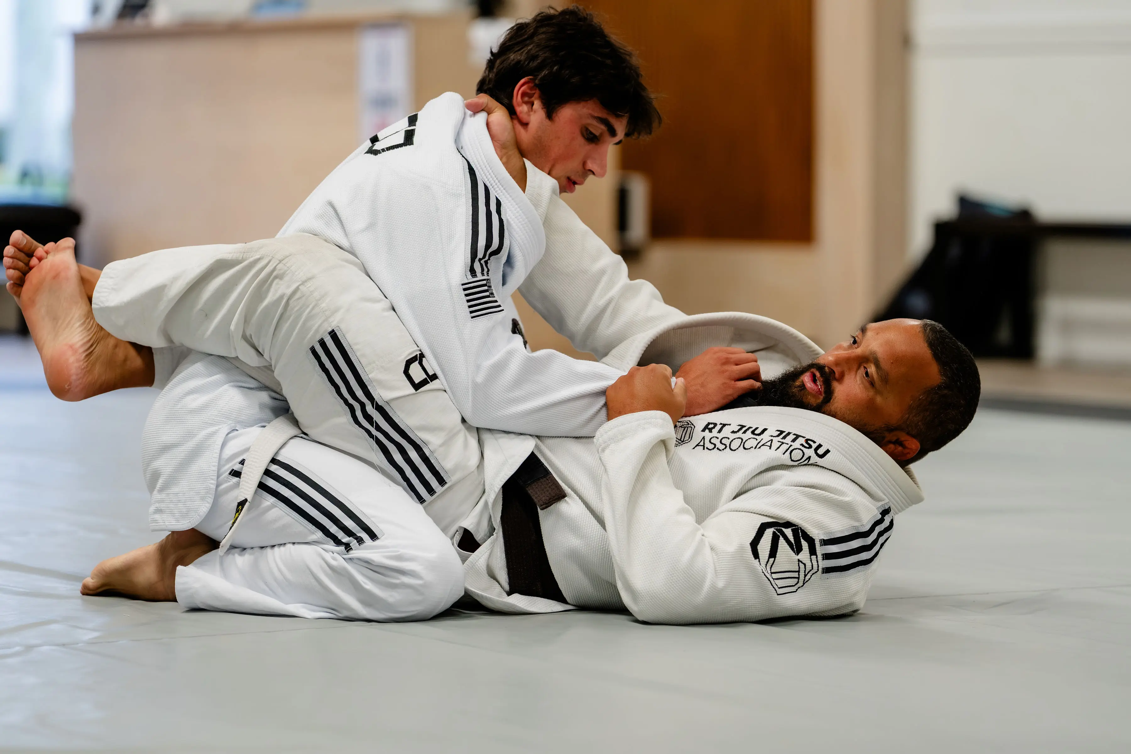 Adults Jiu Jitsu class at RT Beachside: two students in white Gis working from the guard