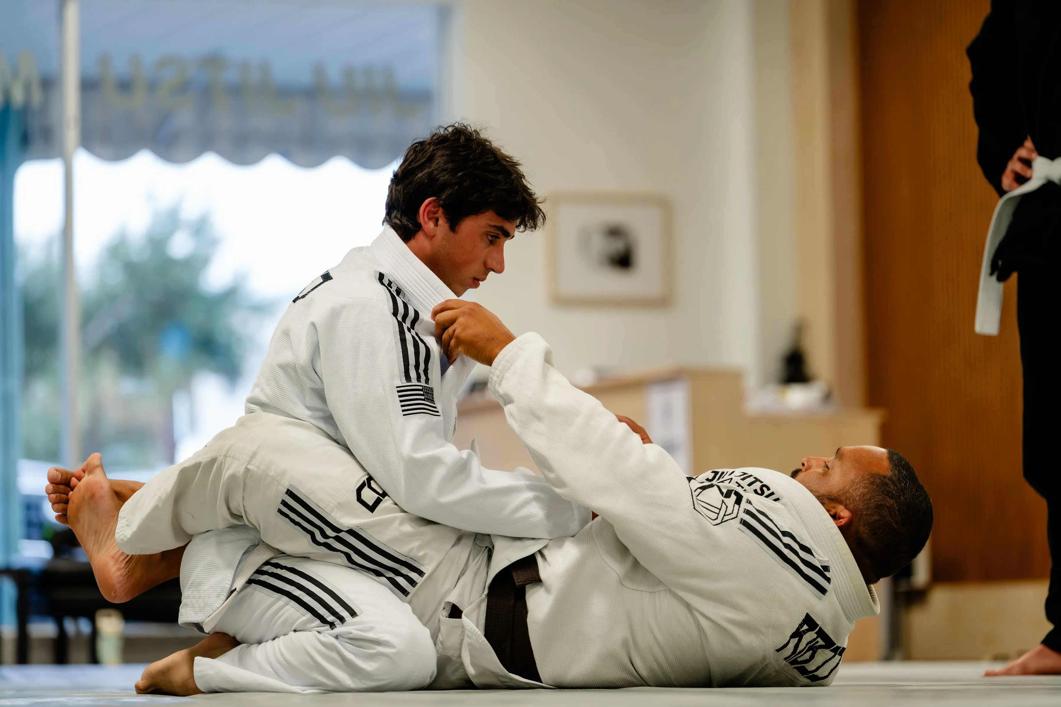 Adults Jiu Jitsu class at RT Beachside: a student passing the guard of a training partner in a white Gi