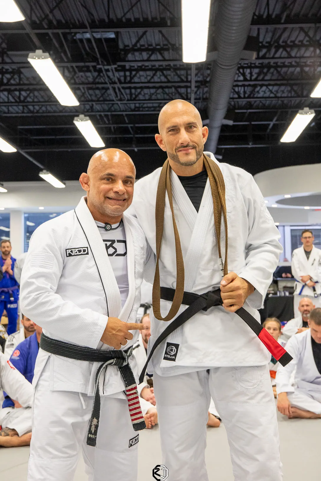 Master Renato Tavares next to an adult student at a belt promotion at RT Headquarters