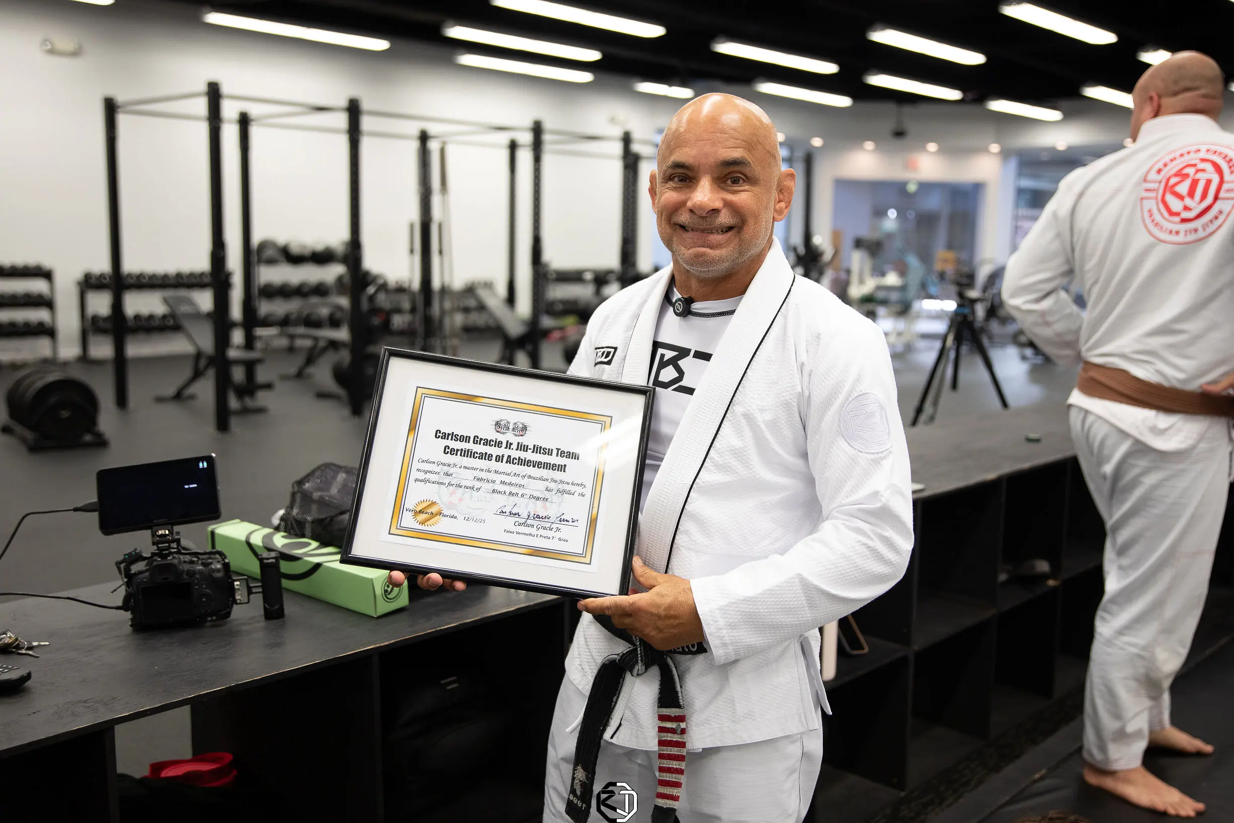Master Renato Tavares smiling and holding a Carlson Gracie Jr. Jiu Jitsu Team certificate at RT Headquarters