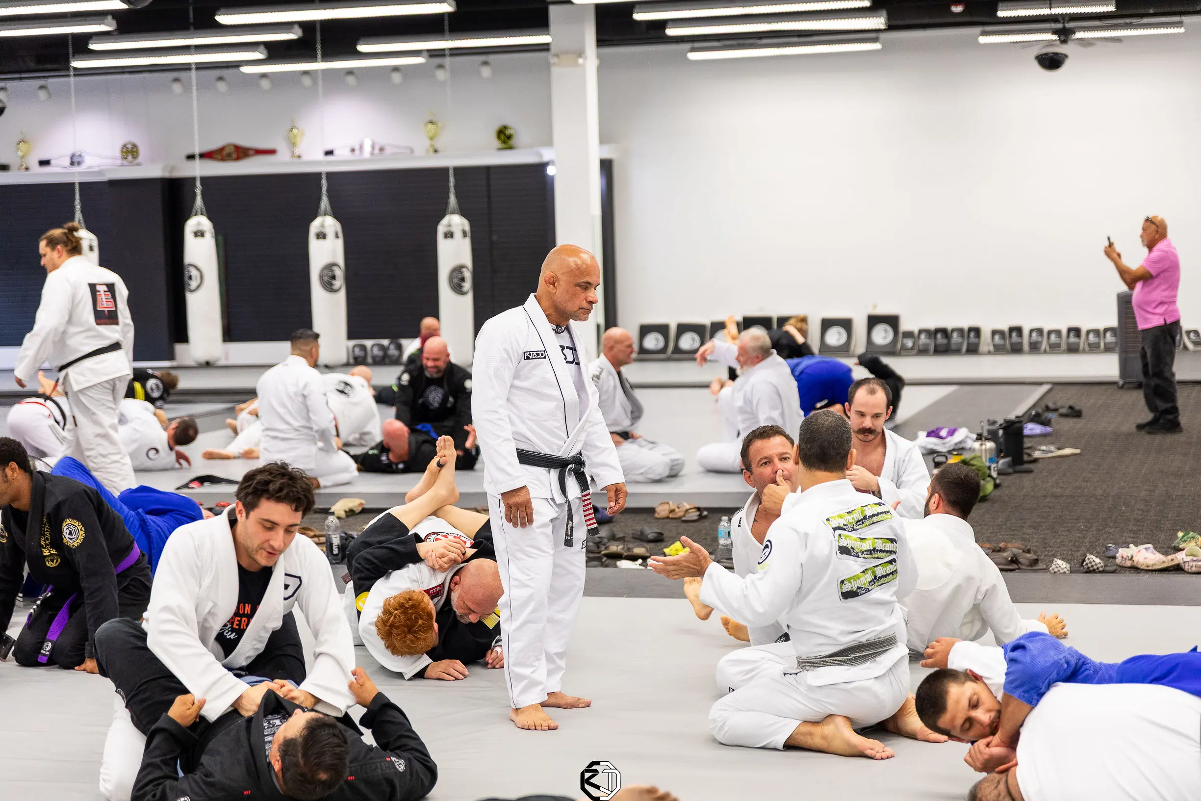 Master Renato Tavares walking the mats during a seminar at RT Headquarters, with pairs of students drilling
