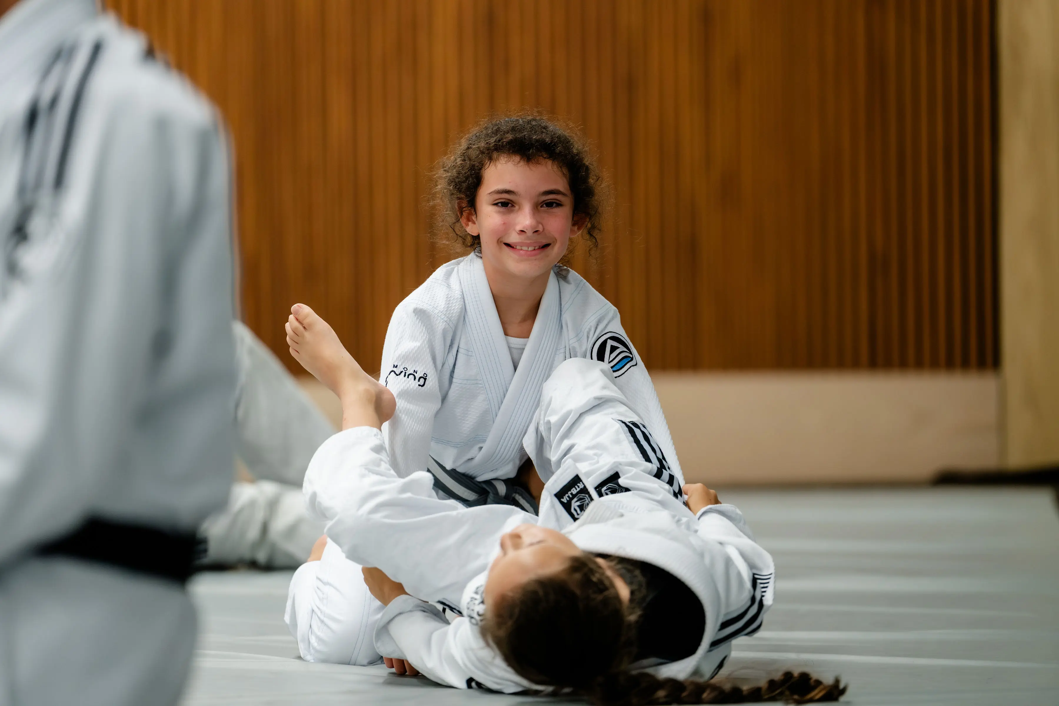 Kids Jiu Jitsu class at RT Beachside: a girl smiling while drilling from the guard