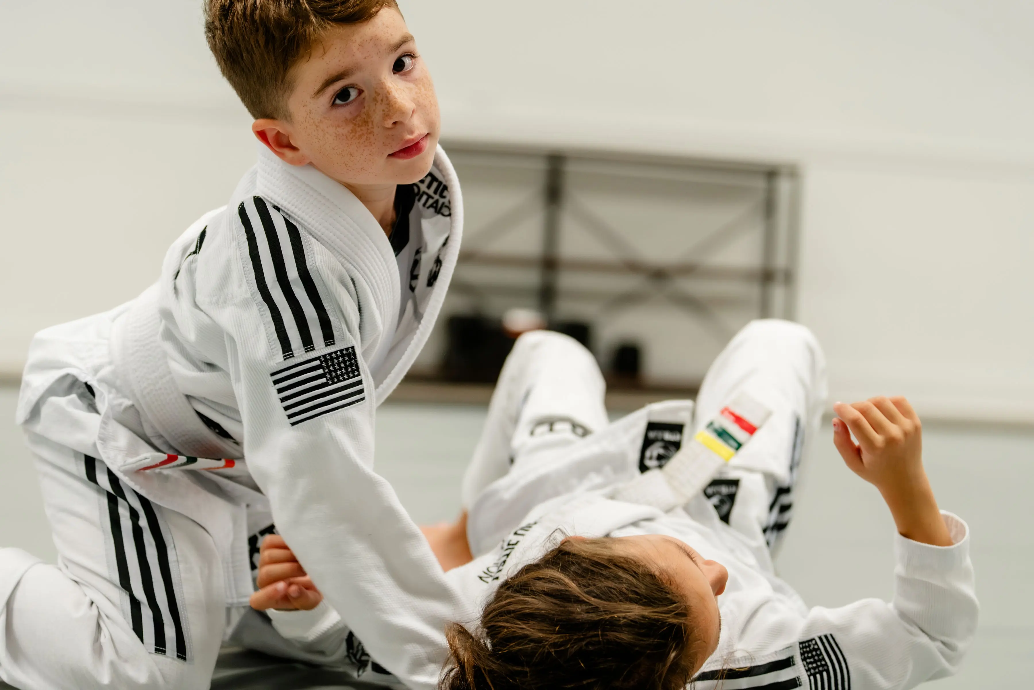 Kids Jiu Jitsu class at RT Beachside: a boy in a white Gi looks up mid-drill