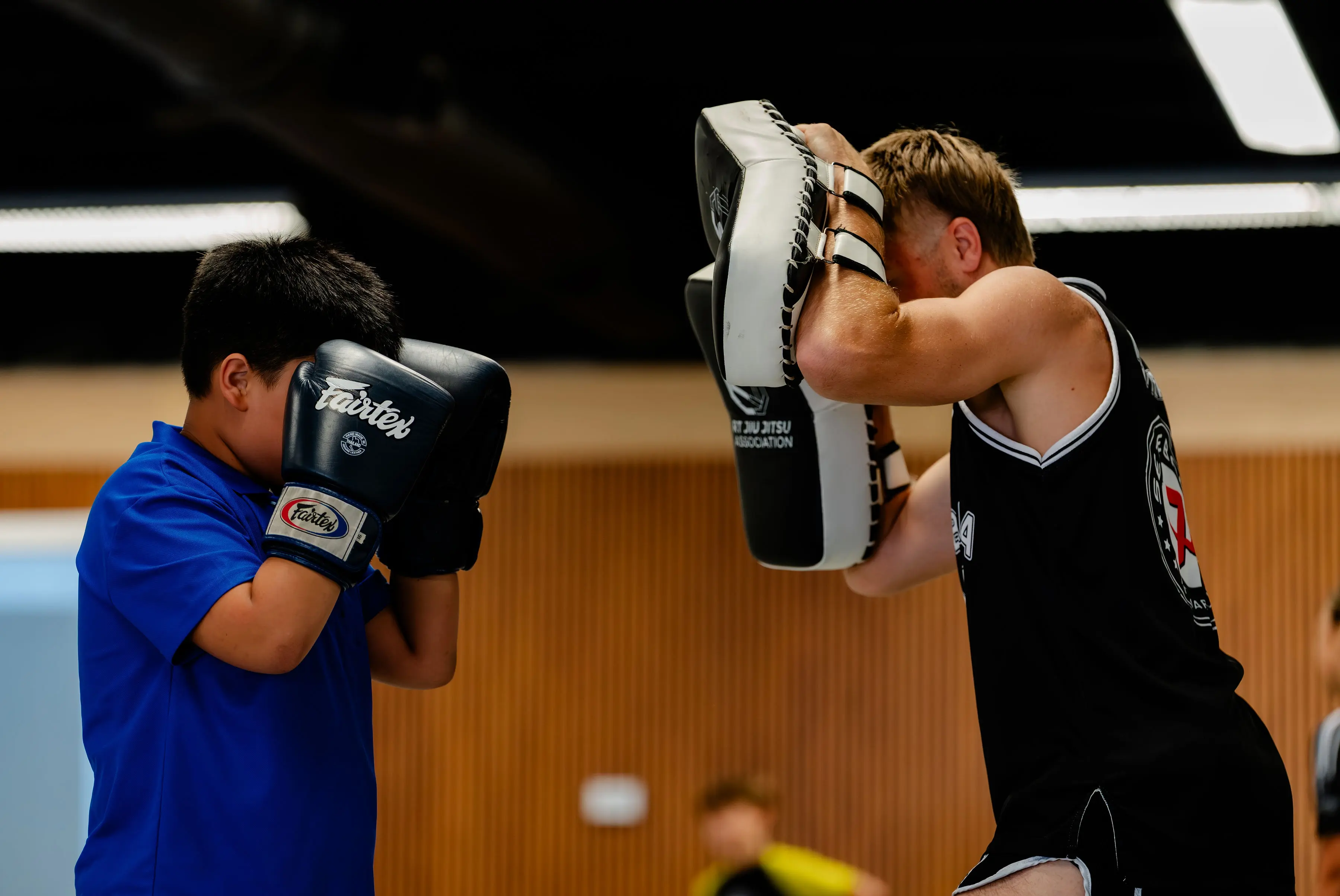 Kids Muay Thai class at RT Beachside: a boy with his gloves up in front of the pad