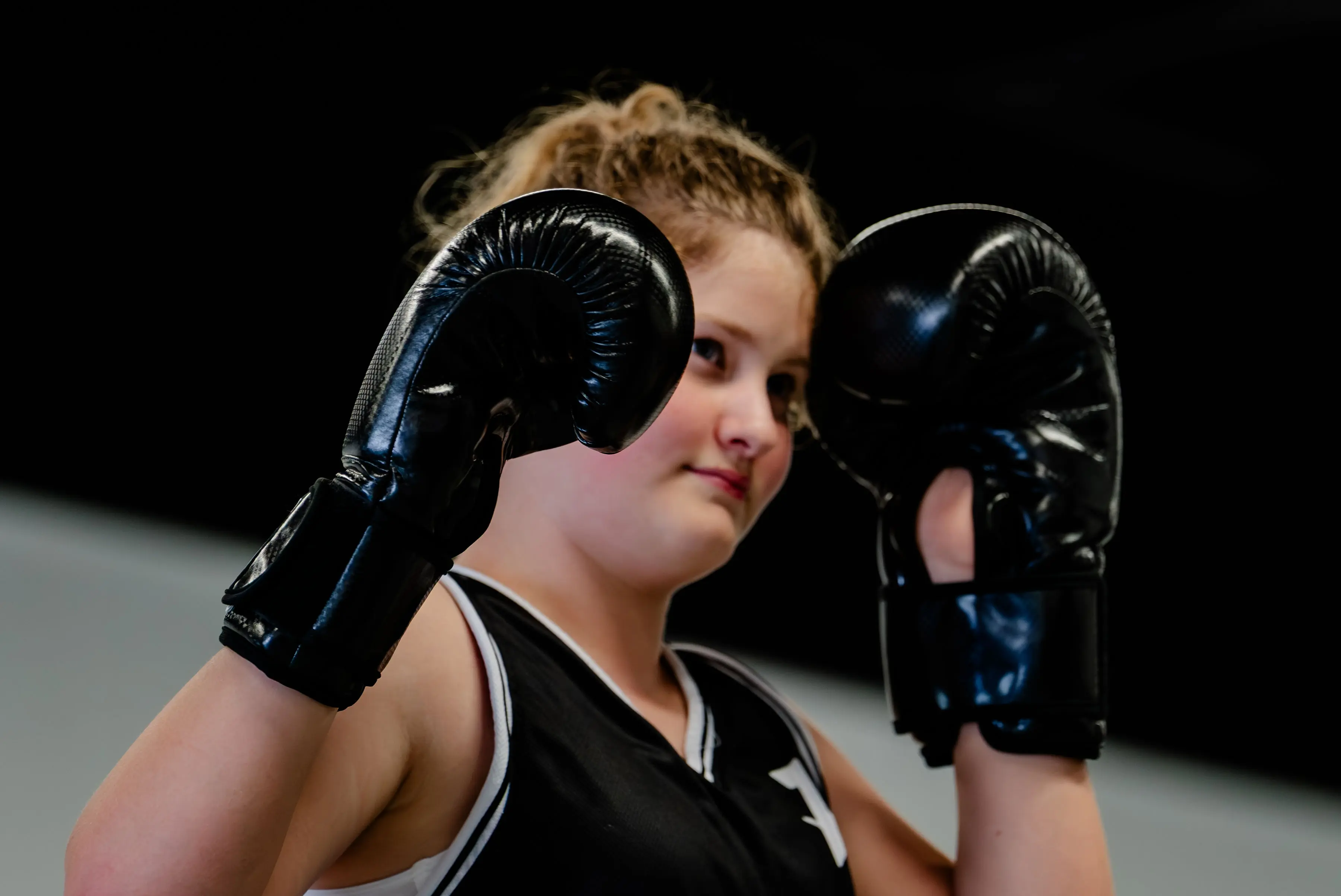 Kids Muay Thai class at RT Beachside: a girl with her gloves up by her face