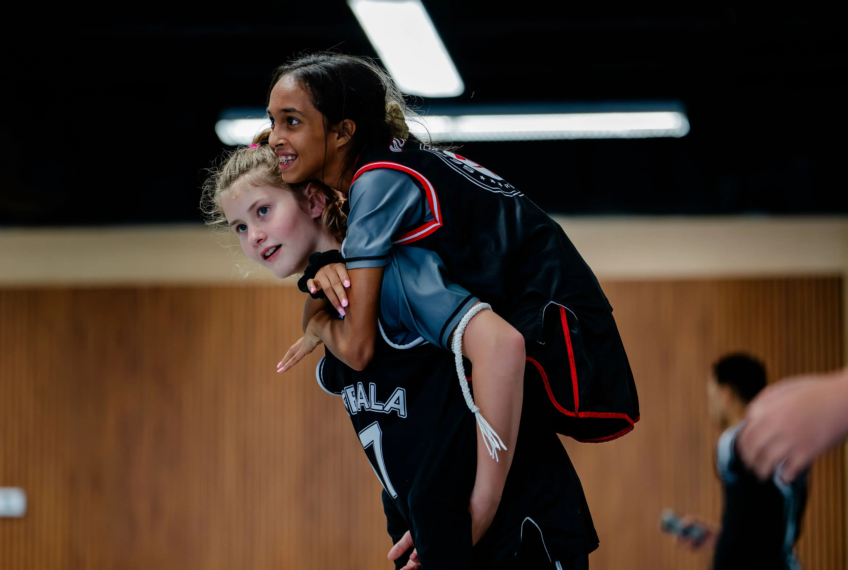 Kids Muay Thai class at RT Beachside: a girl laughing on the instructor's back after class